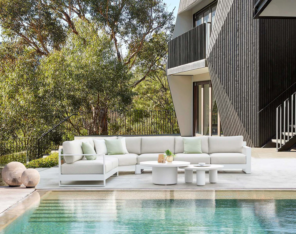 White outdoor lounge set with curved sofa and round coffee table