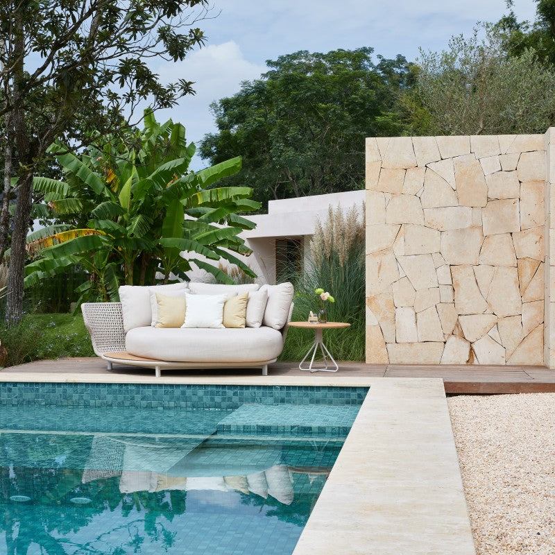 ALMA round outdoor daybed beside a swimming pool and garden