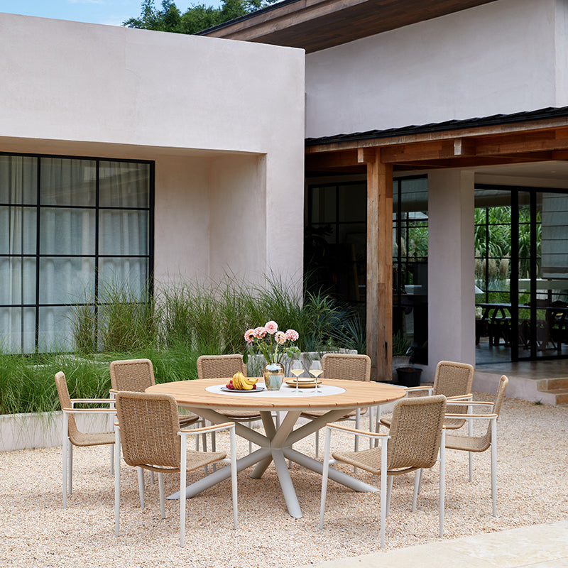 LOOP 8-seater teak round outdoor dining table arranged beside a pool