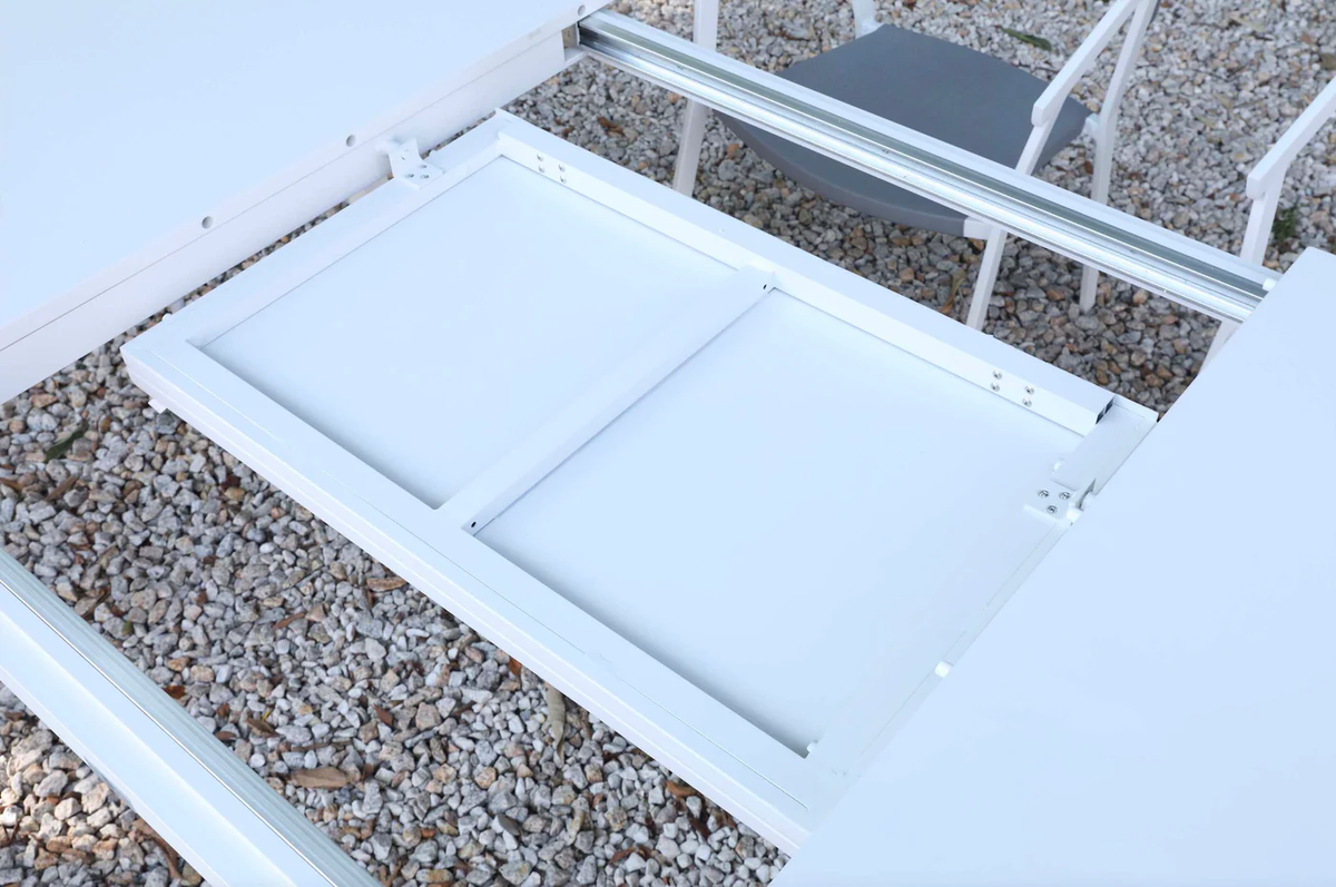 Underside view showing the extension mechanism of the white outdoor dining table