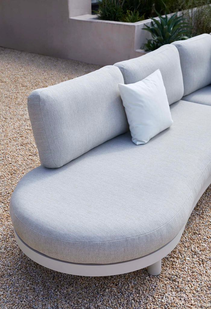 White modular outdoor sofa with curved cushions and throw pillow