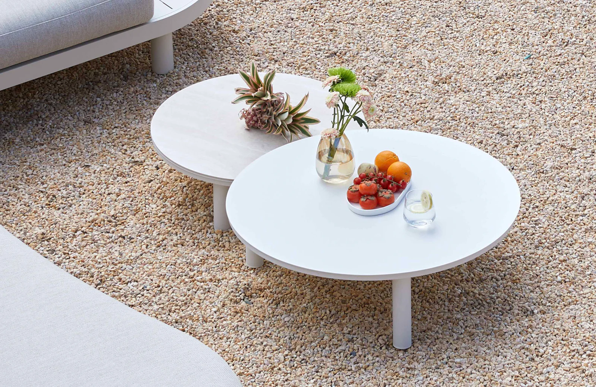 Two white round outdoor coffee tables beside a modular sofa