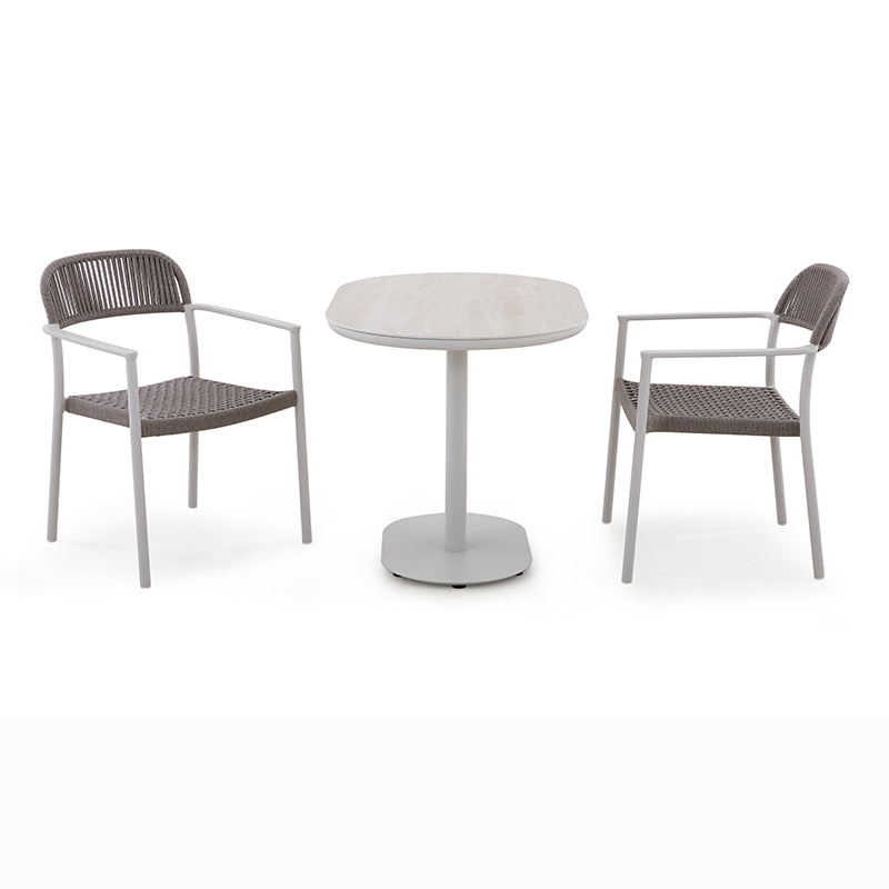 Styled view of the FANO outdoor bistro set with two woven dining armchairs