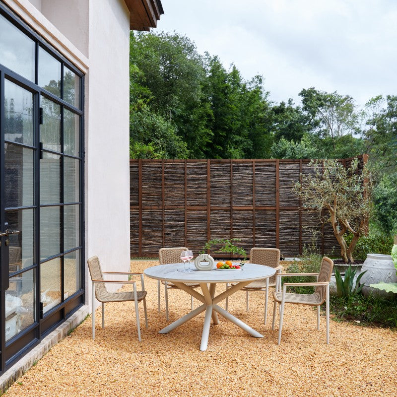 LOOP round outdoor dining table styled with outdoor dining chairs in a garden setting
