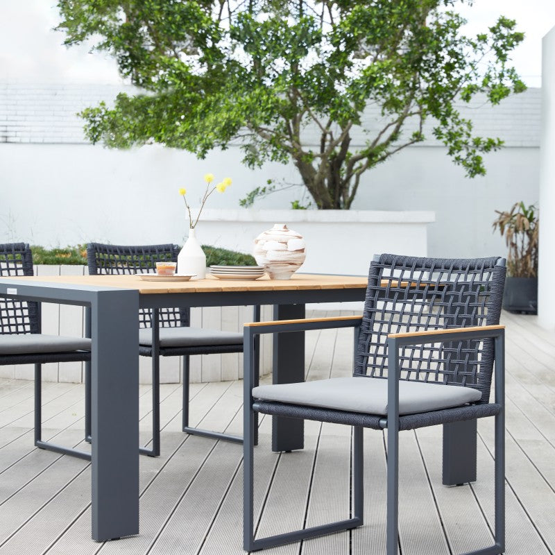Front detail of the SUNRISE black rope-woven outdoor dining armchair with grey cushion