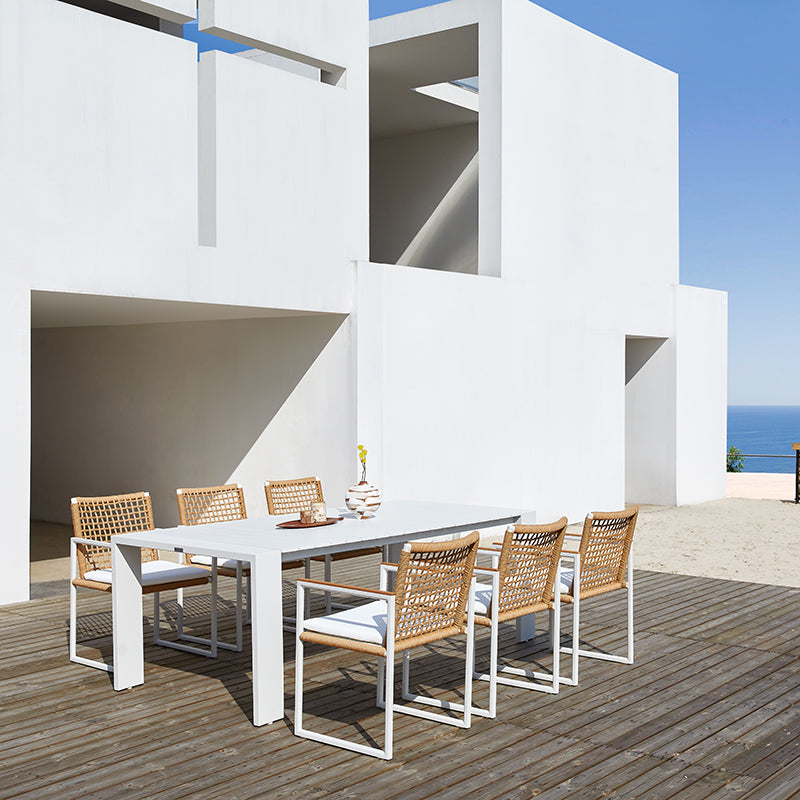 SUNRISE white outdoor dining table arranged for outdoor dining beside a coastal home